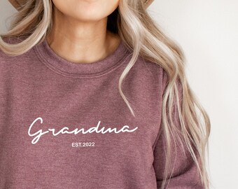 May include: A maroon sweatshirt with the text "Grandma Est. 2022" in white.