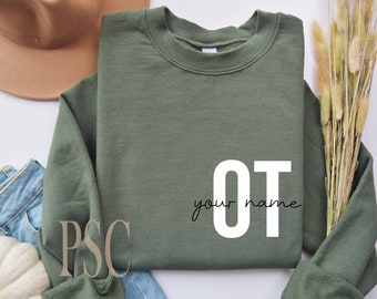 Puede incluir: Una sudadera verde con el texto "OT your name" en letras blancas. La sudadera está colocada sobre una superficie blanca.