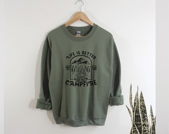 May include: A green sweatshirt with a black graphic print that says "Life is better by the campfire". The graphic features a campfire with flames, mountains, and trees.