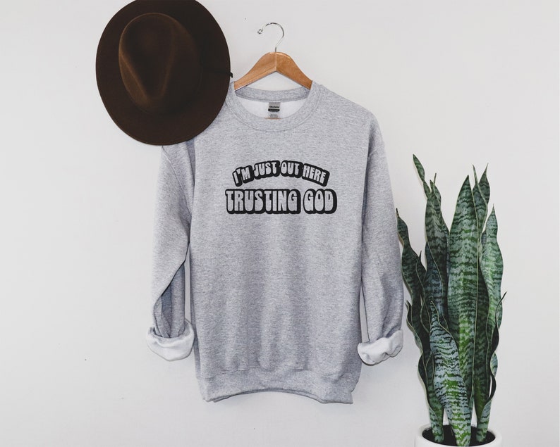 May include: Gray sweatshirt with the text "I'm just out here trusting God" in a retro font.