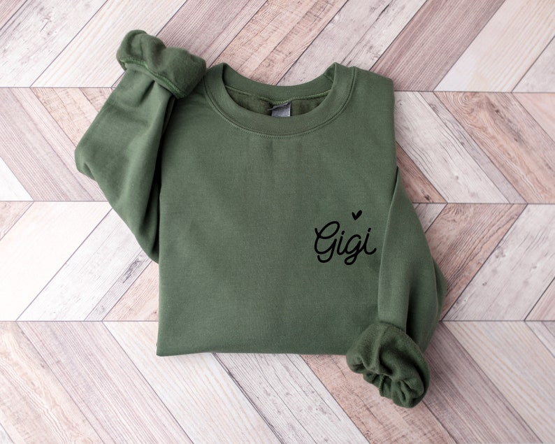 May include: A green sweatshirt with the name "Gigi" and a small heart embroidered on the front.