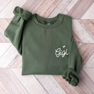May include: A green sweatshirt with the word "Gigi" and a small heart embroidered on the left side.