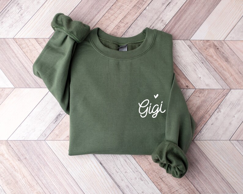 May include: A green sweatshirt with the word "Gigi" and a small heart embroidered on the left side.