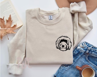 May include: A beige sweatshirt with a black silhouette of a dog's head on the front.