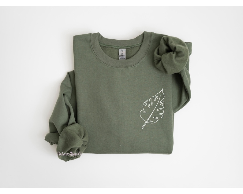 May include: A green sweatshirt with a white outline of a leaf on the left side of the chest.