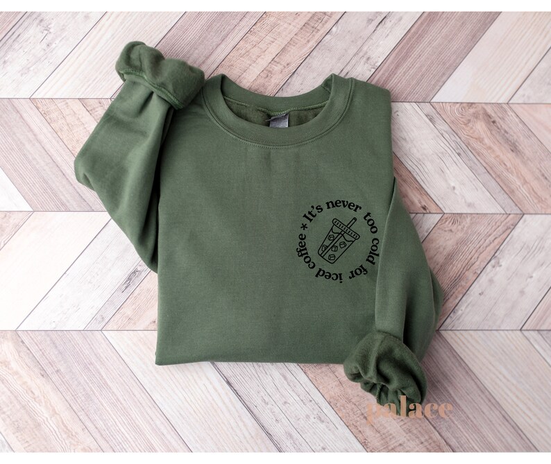 May include: A green sweatshirt with a black graphic that says "It's never too cold for iced coffee" with a drawing of a cup of iced coffee.