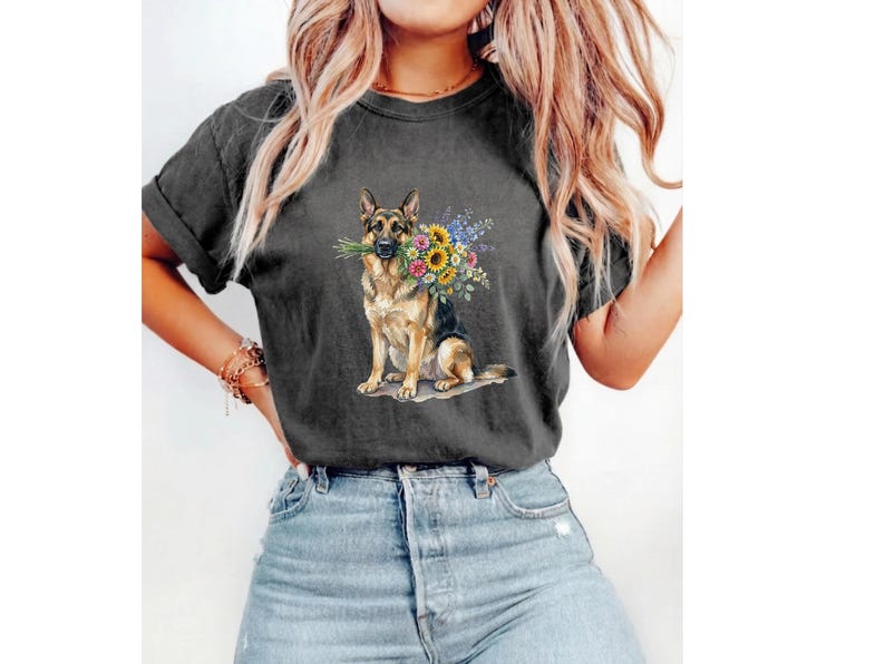 Peut inclure: T-shirt gris fonc&eacute; avec une illustration &agrave; l'aquarelle d'un berger allemand tenant un bouquet de tournesols et d'autres fleurs color&eacute;es. Le chien est assis et le t-shirt a des manches retrouss&eacute;es.