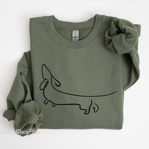 May include: A green sweatshirt with a black line drawing of a dachshund on the front.