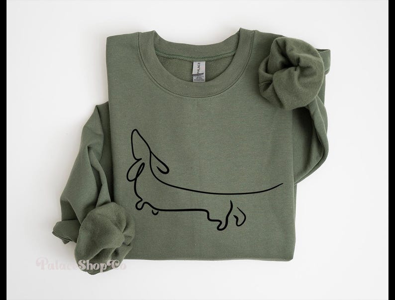 May include: A green sweatshirt with a black line drawing of a dachshund on the front.