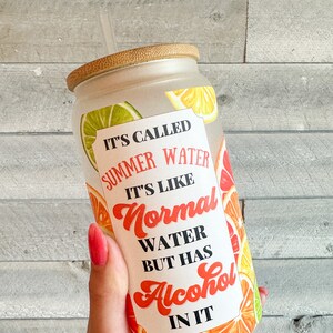 May include: A frosted glass tumbler with a bamboo lid and a straw. The tumbler has a colorful citrus fruit design and the text "It's called summer water. It's like normal water but has alcohol in it."