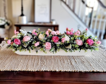 May include: A white ceramic trough planter filled with a floral arrangement of pink and white roses, green eucalyptus leaves, and small pink flowers.