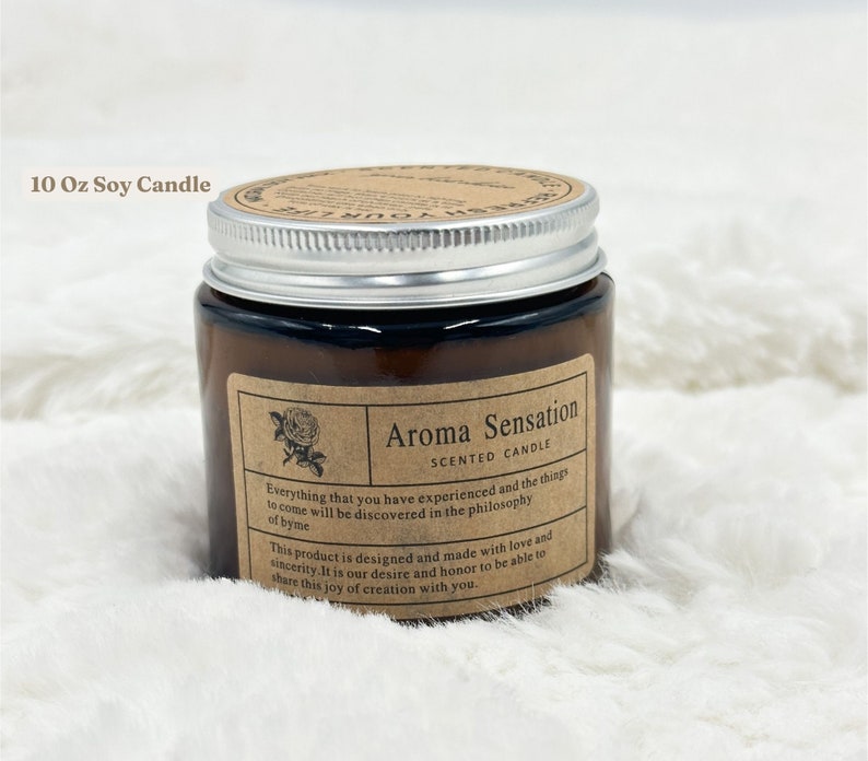 May include: Aroma Sensation scented soy candle in a brown glass jar with a silver lid. The label includes a rose illustration and text that reads "Everything that you have experienced and the things to come will be discovered in the philosophy of byme."