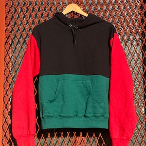 Puede incluir: Una sudadera con capucha de color negro, verde y rojo con capucha con cordón y bolsillo canguro.