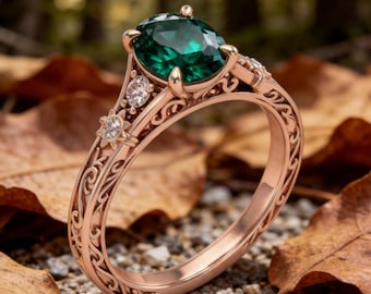 May include: A rose gold ring featuring a large, round, deep green gemstone as the center stone. The band is crafted with intricate, swirling metal filigree patterns and is accented with two small, clear, round-cut stones on each side.