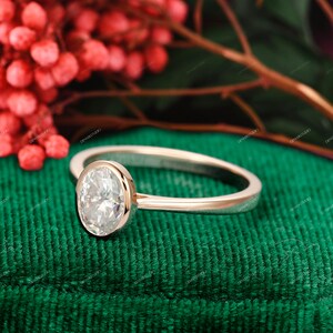 Op de afbeelding: Een verlovingsring van ros&eacute;goud met een bezel-setting met een grote ovale diamant.