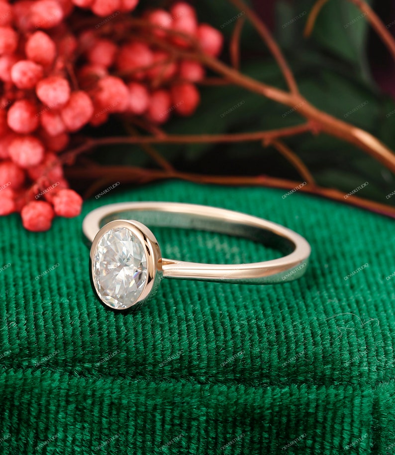 Op de afbeelding: Een verlovingsring van ros&eacute;goud met een bezel-setting met een grote ovale diamant.