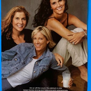 May include: Three women wearing denim jackets and white shirts pose for a photo. The woman in the middle is holding a glass of milk. The text "got milk?" is printed at the bottom of the image.