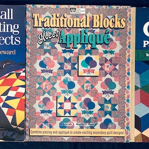 May include: Three quilting books are displayed, each with a different cover design. The titles include "Small Quilting Projects," "Traditional Blocks Meet Appliqué," and "Sunset Quilting, Patchwork & Appliqué." The books feature colorful quilt patterns and designs, showcasing various quilting techniques.