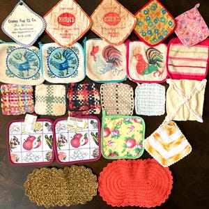 May include: A collection of twenty-two assorted square and oval potholders and hot pads in various colors, patterns, and textures. The items feature printed text, rooster illustrations, fruit motifs, woven checkered designs, and solid crochet patterns.