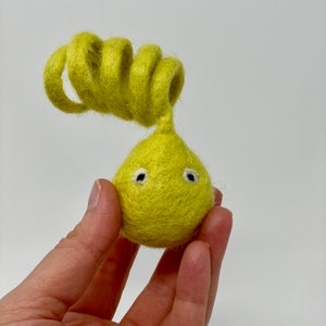 May include: A yellow felt toy with curly yellow felt hair and two white eyes.