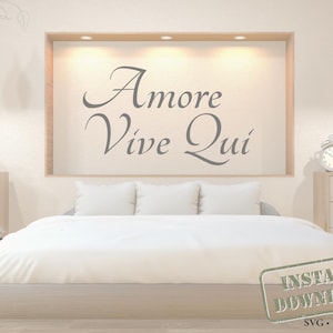 Peut inclure: Une scène de chambre à coucher avec un lit avec une literie et des oreillers blancs. Au-dessus du lit, une œuvre d'art murale encadrée de bois affiche les mots "Amore Vive Qui" en écriture élégante. La pièce est décorée de lampes suspendues et de plantes.