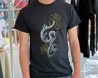 May include: Black t-shirt with a white and gold graphic print of a snake, flowers, and leaves.