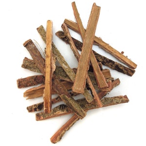May include: A pile of dried bark sticks, some with a rough, brown outer layer and others with a smooth, light brown inner layer.
