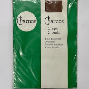 May include: A package of brown sheer stockings with the brand name "Charnos Crepe Clouds" printed on the front. The package is green and white and says "Fully Fashioned 30 Denier Seamed Stockings Crepe Stretch."