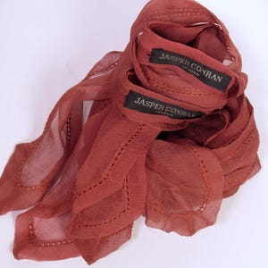 May include: Two rust-coloured sheer scarves with scalloped edges and the text "Jasper Conran London" on the labels.