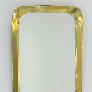 May include: A rectangular mirror with a thick, gold-coloured metal frame. The frame has a slightly rounded edge.