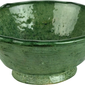 May include: A green ceramic bowl with a slightly uneven rim and a small foot. The bowl has a rustic, handmade look.