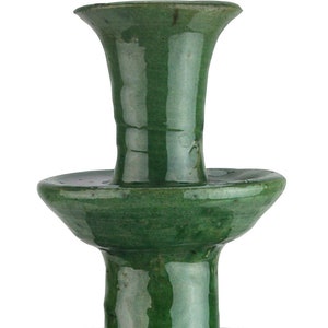 May include: A green ceramic candlestick with three tiers. The candlestick has a smooth, glossy finish and a slightly rounded base.