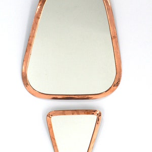 Peut inclure: Deux miroirs encadres de cuivre, un grand de forme ovale, l'autre plus petit et de forme triangulaire.