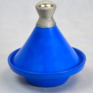 Op de afbeelding: Een blauwe keramische tajine met een zilveren deksel. De tajine is een traditionele Marokkaanse kookpot.