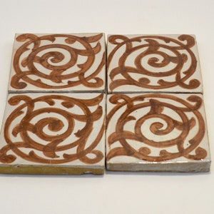 May include: Four square ceramic tiles with a brown and white geometric pattern. The pattern features a swirling design with a central circle.