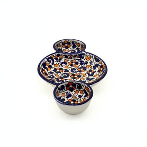 May include: A white ceramic serving dish with three sections. The dish is decorated with a blue and orange floral pattern.