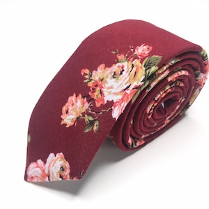 May include: A burgundy skinny tie with a floral pattern featuring pink and white roses.