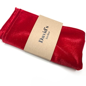 Puede incluir: Un pañuelo de bolsillo de terciopelo rojo con una etiqueta de papel marrón que dice "David's Atelier".