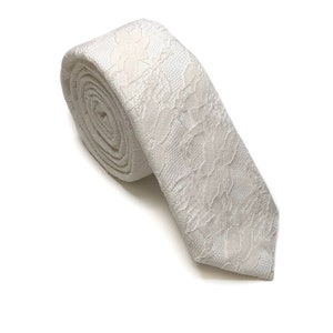 Puede incluir: Una corbata fina blanca con un delicado estampado floral.