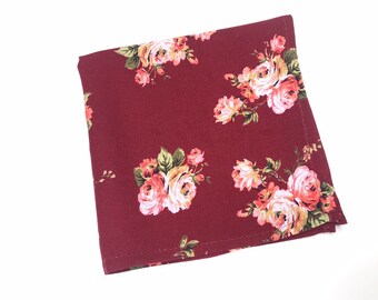 May include: A burgundy fabric square with a floral pattern of pink and white roses. The fabric has a subtle sheen and a soft texture.