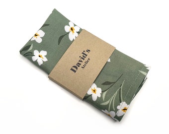 Può includere: Un fazzoletto di cotone verde con un motivo floreale bianco e un'etichetta marrone che dice "David's Atelier".