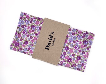 May include: A white cotton pocket square with a purple and light blue floral pattern. The pocket square is folded and packaged with a brown paper label that reads "David's Atelier".