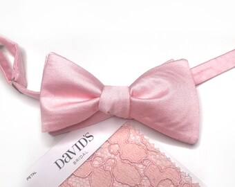 May include: A pink satin bow tie with a matching pink lace fabric swatch. The fabric swatch has the text "David's Bridal" and "Petal" printed on it.