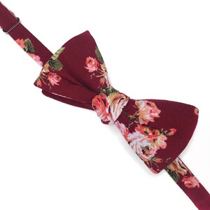 May include: A burgundy bow tie with a floral pattern featuring pink and white roses.