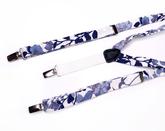 May include: White suspenders with a blue floral pattern. The suspenders have adjustable straps and metal clips.