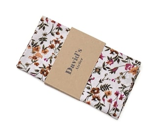May include: White floral pocket square with a brown paper band that reads "David's Atelier". The pocket square features a repeating pattern of orange, pink, and green flowers and leaves.