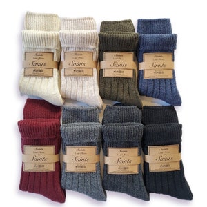 K&ouml;nnte beinhalten: Acht Paar Socken in verschiedenen Farben, darunter Beige, Gr&uuml;n, Grau und Burgunderrot. Jedes Paar hat ein braunes Etikett mit dem Text "Saints" und "L's Wool".