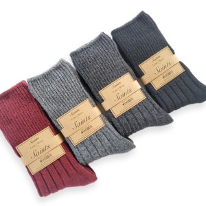 K&ouml;nnte beinhalten: Vier Paar gerippte Socken in Burgunderrot, Grau, Dunkelgrau und Schwarz. Jedes Paar hat ein braunes Papieretikett mit dem aufgedruckten Text "Saints Lamb's Wool Saints".