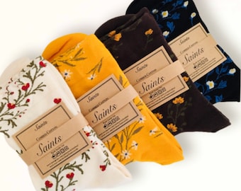 May include: Four pairs of socks with floral patterns. The socks are in white, yellow, brown, and black. Each pair has a small tag with the word "Saints" and the text "Combed Cotton".