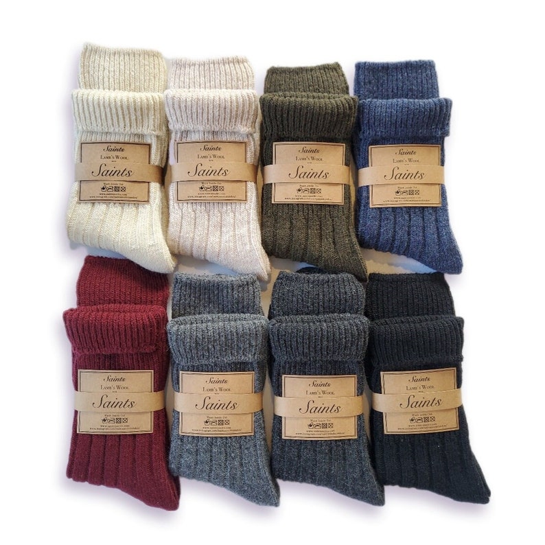K&ouml;nnte beinhalten: Acht Paar Socken in verschiedenen Farben, darunter Beige, Gr&uuml;n, Grau und Burgunderrot. Jedes Paar hat ein braunes Etikett mit dem Text "Saints" und "L's Wool".